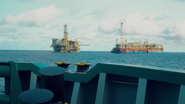 FPSO tanker vessel near Oil Rig platform. Offshore oil and gas industry. Flare is burning with smoke. View from supply vessel.