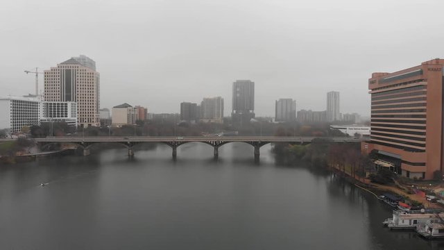 A drone flies low over the Colorado River and Ladybird Lake in downtown Austin, Texas capturing images on a foggy, rainy day.