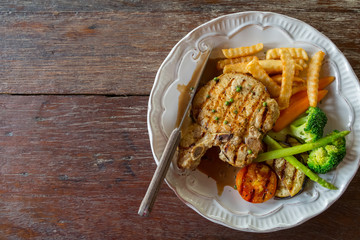 Black pepper pork chop in white plate on wooden table