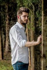 Handsome boy relaxing in the woods, propped up in one of the trees.