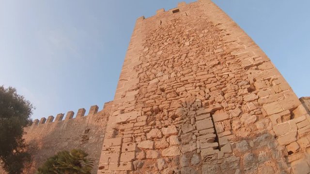 Closeup of ancient stone fortress wall. Old medieval fortification built in the XIV century. Capdepera Castle, Mallorca, Balearic islands, Spain. 4K footage during sunset with sun in backlight