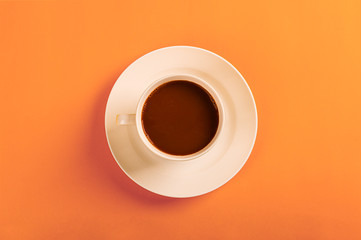 Top view.Cup of coffee on orange background.