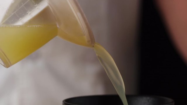 Pouring fresh lemons juice into bowl macro shot, cooking process, making lemonade, slow motion, isolated, shot on Red Weapon Helium 8k