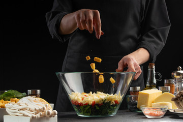 A professional chef cooks a fresh and healthy Italian salad sprinkling crackers, Freezing in motion. Organic and wholesome food. Healthy nutrition and vitamins. Advertising photo