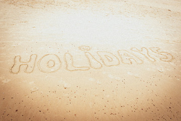 Odręczny napis holidays - wakacje  na piasku nad morzem © Michal Lech