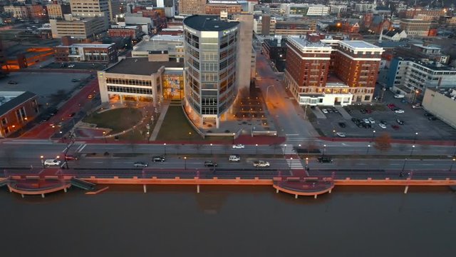 Tracking shot of evening traffic alongside the flooded Evansville Riverfront pulling out to show the visitor's Bureau and surrounding neighborhood . Shot with Phantom Four Pro.