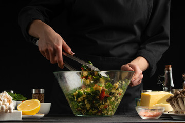 Chef mixes salad. Vegetarian and fresh food, gastronomy and cooking, recipe book and recipes. On a black background