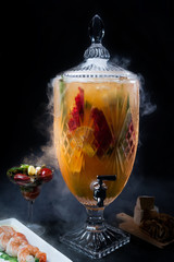 Crystal Chalice drink with orange and fruits with a side of shrimp cocktail and black background
