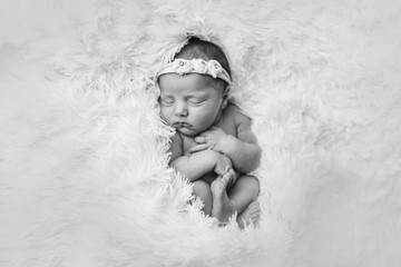 portrait of a sleeping newborn baby in a headband with flower. Health concept: IVF, baby accessories