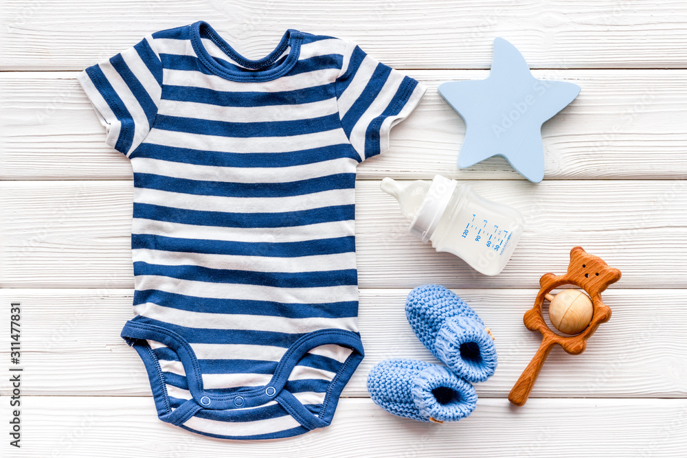 Wall mural blue bodysuit for baby boy near children's accessories on white wooden background top-down