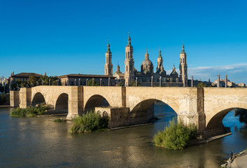 Fototapeta na wymiar Puente de Piedra bridge across the river Ebro and the ancient church Basilica del Pillar in the Spanish city Zaragoza