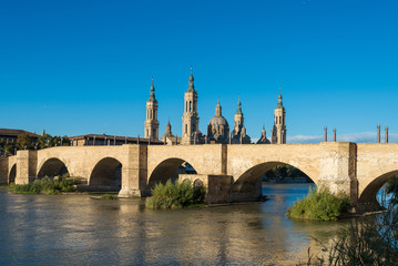 Fototapeta na wymiar Puente de Piedra bridge across the river Ebro and the ancient church Basilica del Pillar in the Spanish city Zaragoza