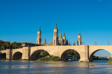 Puente de Piedra bridge across the river Ebro and the ancient church Basilica del Pillar in the...