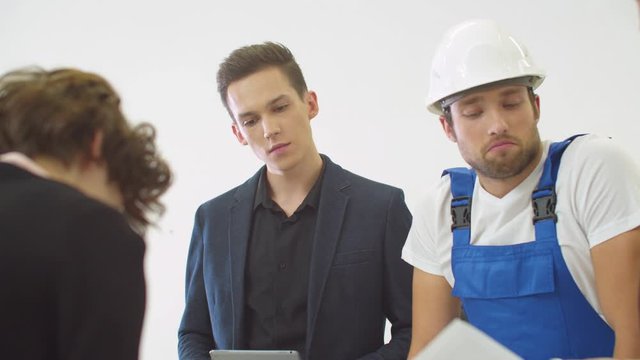 Gruop of engineers work on proect of houses with builder in helmet