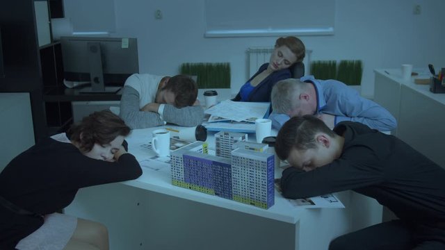 Model of house on table, workmates sit and sleep