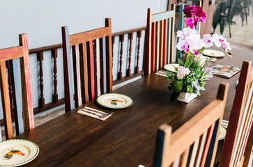 Thai restaurant table with cutlery, plate, glass, napkins and orchids on the table. 