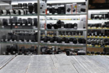 Obraz premium empty wooden table on the background of range of digital mirrorless and SLR cameras and lenses