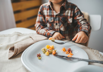 Obraz na płótnie Canvas Child boy with plate of tasty paste in kitchen. Closeup