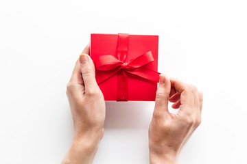 Unpack a gift on Valentine's Day. Women hand hold ribbon tied present box on white background top-down