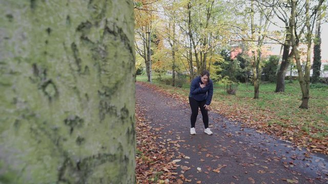 Breathless woman after jogging in a park during autumn.