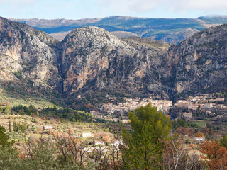 Fototapeta na wymiar Village of Moustiers-Sainte-Marie in Provence built in a platform terraces along a cliff between lake of Sainte-Croix and Gorges du Verdon