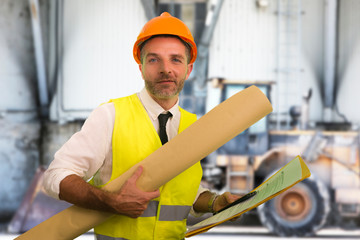 construction work lifestyle portrait of young happy and attractive engineer or building contractor holding blueprints wearing constructor hardhat smiling confident