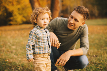 Close up photo of dad with his little boy playing outdoor in park during autumn