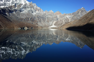 Fototapeta na wymiar Mountain reflecting in calm Gokyo lake with view of Renjo La pass. Hiking in Nepal Himalayas