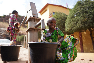 Two Colorful Dressed African Girls Fetching Water at the Borehole