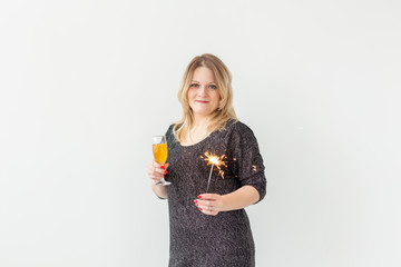 Holidays, christmas, birthday and new year concept - Woman celebrate and holds wine in a glass and sparkler over white background, close-up
