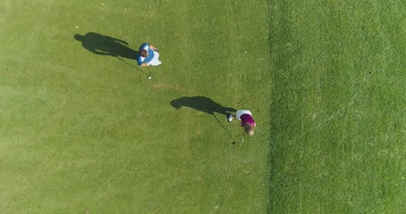 Green park, man trainer teaches woman to play Golf, woman hits the ball, golf course in forest area, green lawn, view from above.