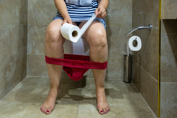 Woman is sitting on a toilet with paper