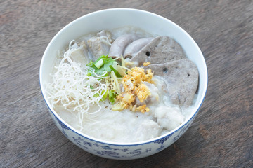 Congee with minced pork, braised pork filling, boiled pork liver, fried garlics minced pork in white bowl. Asian breakfast.