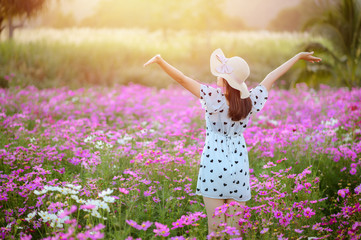 Carefree Happy woman enjoying nature on cosmos flower field. Beauty Girl Outdoor. Freedom concept.