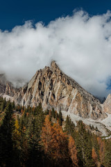 Colourful forest and Dolomite mountains surrounded by clouds in South Tyrol, Italy /View from Lago di Sorapis hiking trail / High ISO image