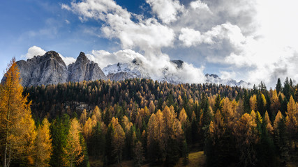 Colourful forest and Dolomite mountains surrounded by clouds in South Tyrol, Italy /View from Lago di Sorapis hiking trail / High ISO image