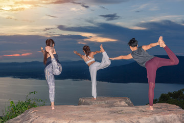 Three Woman doing yoga asana Natarajasana - Lord of the dance pose outdoors on sunset in Himalayas....