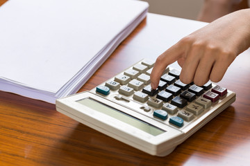 Closeup office female finger pressing on calculator.