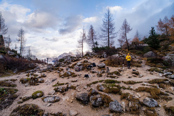 Male photogrpher in yellow with drone remote on the ''lago di sorapis'' trail in Italian alps / ...