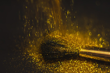 texture of gold glitter on the makeup brush and design. On a black background. Selective Focus