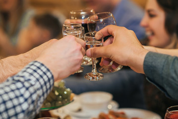 hands of a group of friends clinking glasses of alcoholic beverage and toasting and congratulating