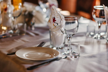 set of empty glasses and plates with Cutlery on a white tablecloth on the table in the restaurant