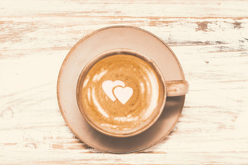 Coffee cup cappuccino or latte  with hearts on foam on vintage wooden background. Holiday coffee...