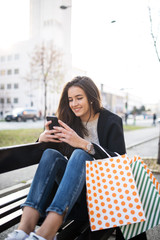 Fototapeta premium Beautiful woman siting on a bench and typing a message