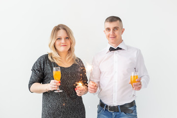 Fototapeta premium Holidays, christmas, valentine's day and new year concept - Woman and man celebrate and holds wine in a glass over white background