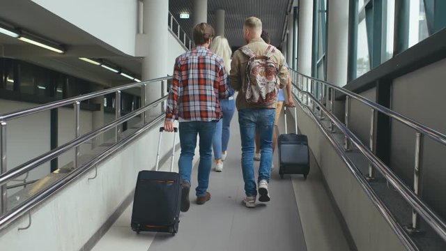 Four young people with luggage going to boarding in airport or train station