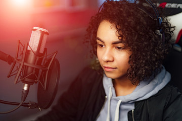 A woman is in front of a microphone in the broadcasting studio. Curly hair. Love my work. Closeup