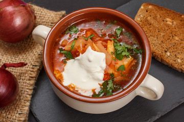Ukrainian traditional borsch with bread on black background.