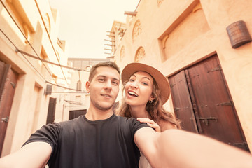 A happy couple takes a selfie against the backdrop of ancient Arabic architecture in the old town...