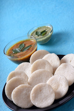 Idli with Sambar and coconut chutney on blue background, Indian Dish : south Indian favourite food rava idli or semolina idly or rava idly, served with sambar and green coconut chutney.